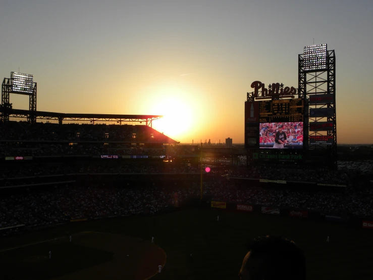 the sun is setting over a baseball stadium