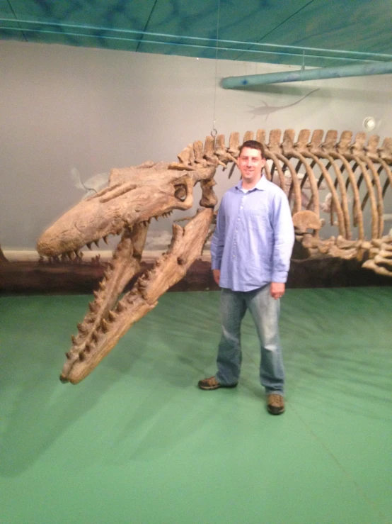 man standing by an animal skeleton with a smile on his face