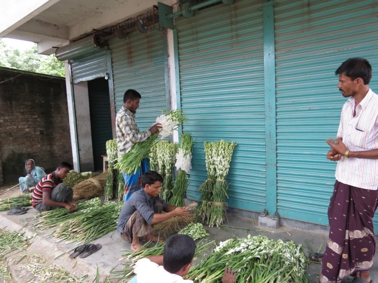 some people sitting around green onions near a building