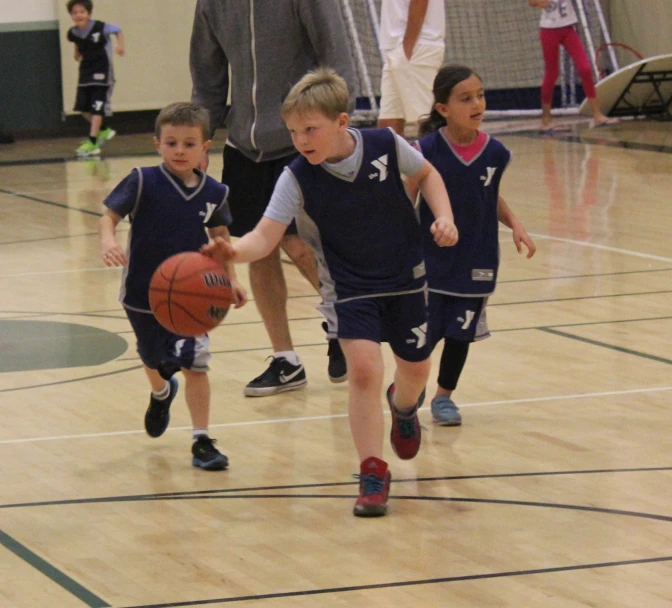 several children run on a court with a basketball