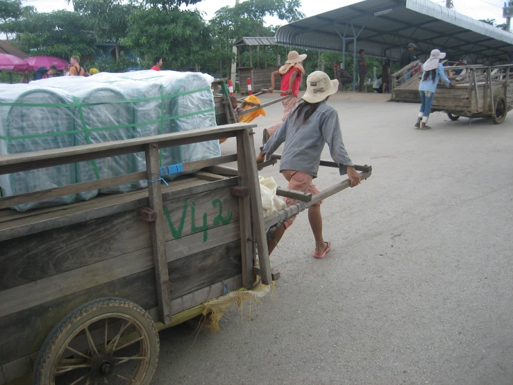 two people on a rural road hing a truck full of hay