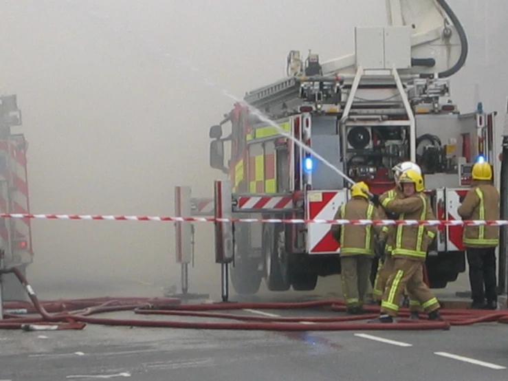 a group of firefighters on the street trying to extinguist a fire