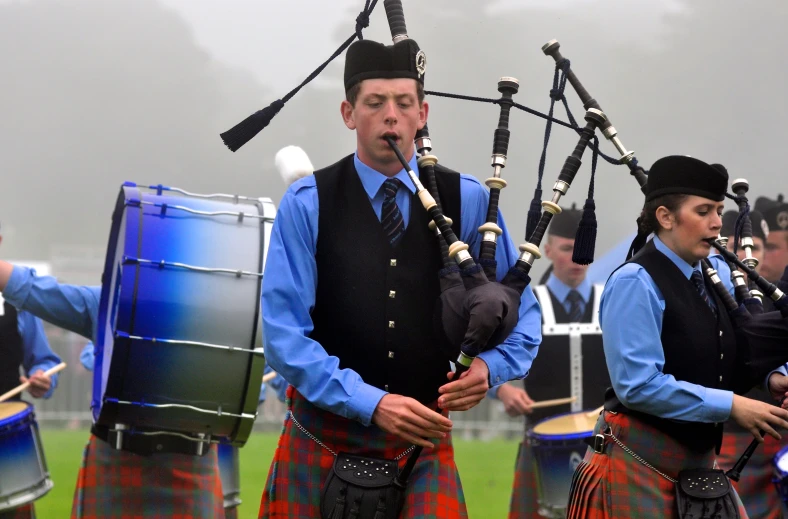 several pipes playing for a band while people watch