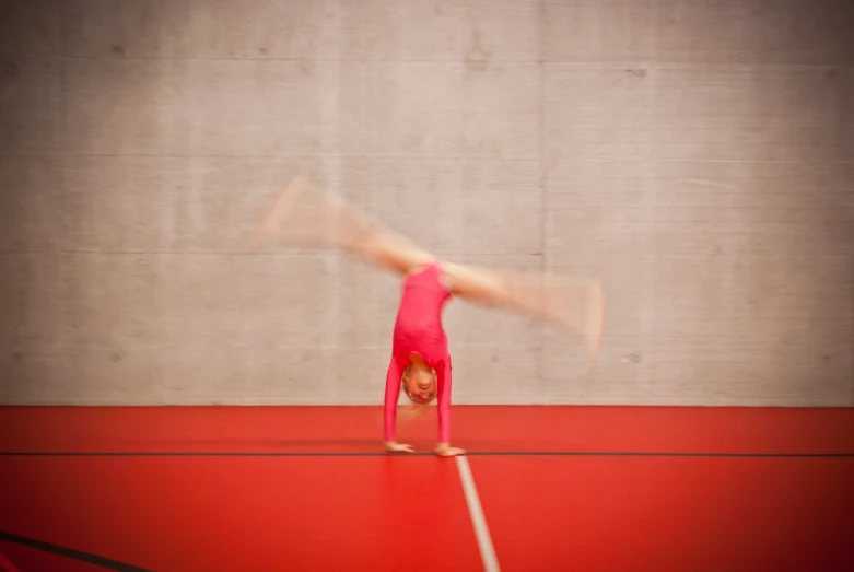 a woman doing gymnastics on a large red surface