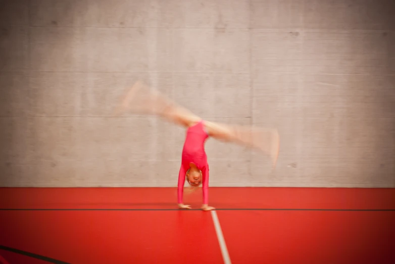 a woman doing gymnastics on a large red surface