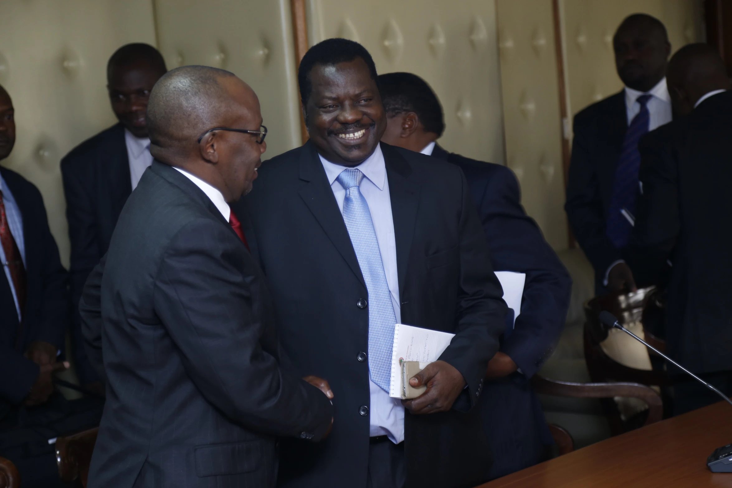 two men in suits meeting one another and smiling