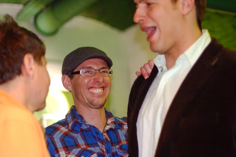 three men laugh together as one is getting his collar adjusted