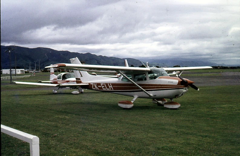 two small airplanes are sitting on some grass