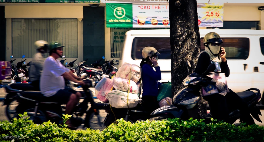 motorcyclists riding past parked cars on a busy street