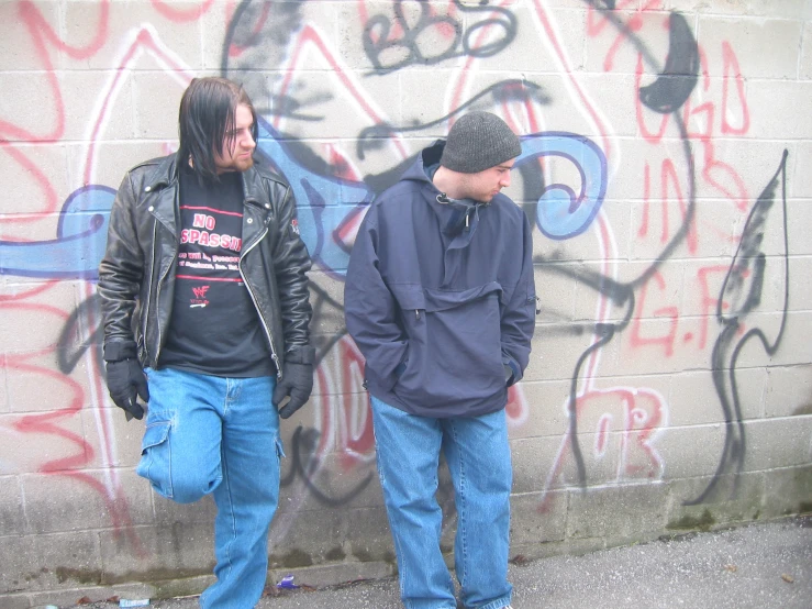 two guys standing in front of a wall