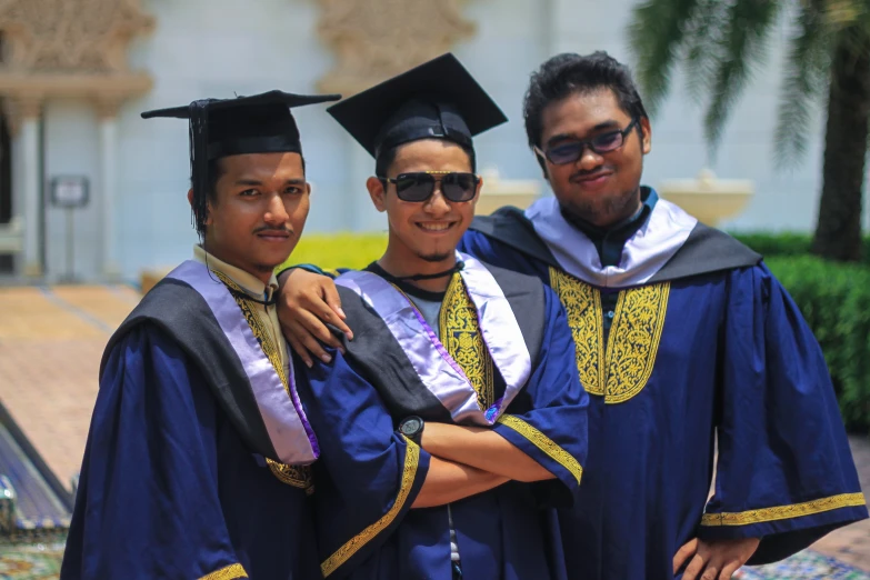 two male graduates stand with their arms around one another