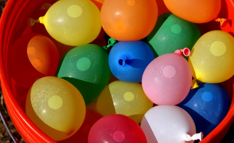 small toy balloons sit in an orange bucket