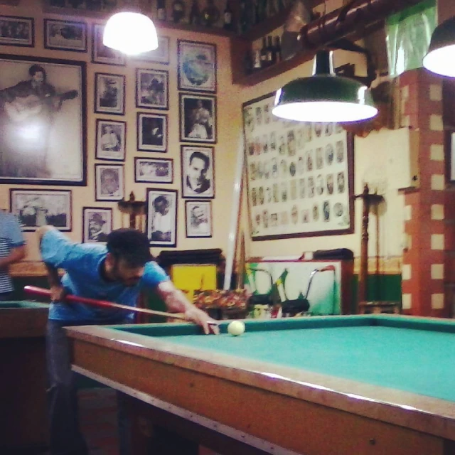 a man playing billiard in a room filled with pictures