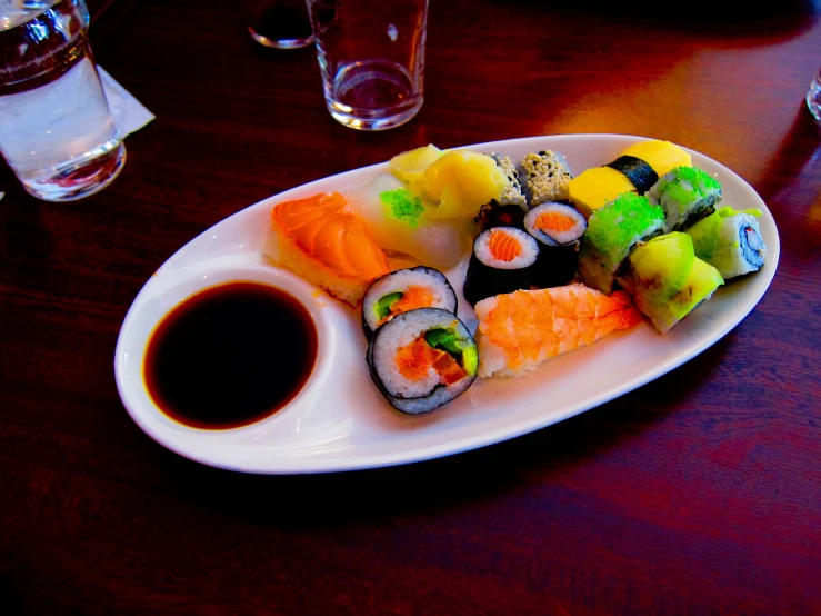 a plate of sushi on a table with cups of water