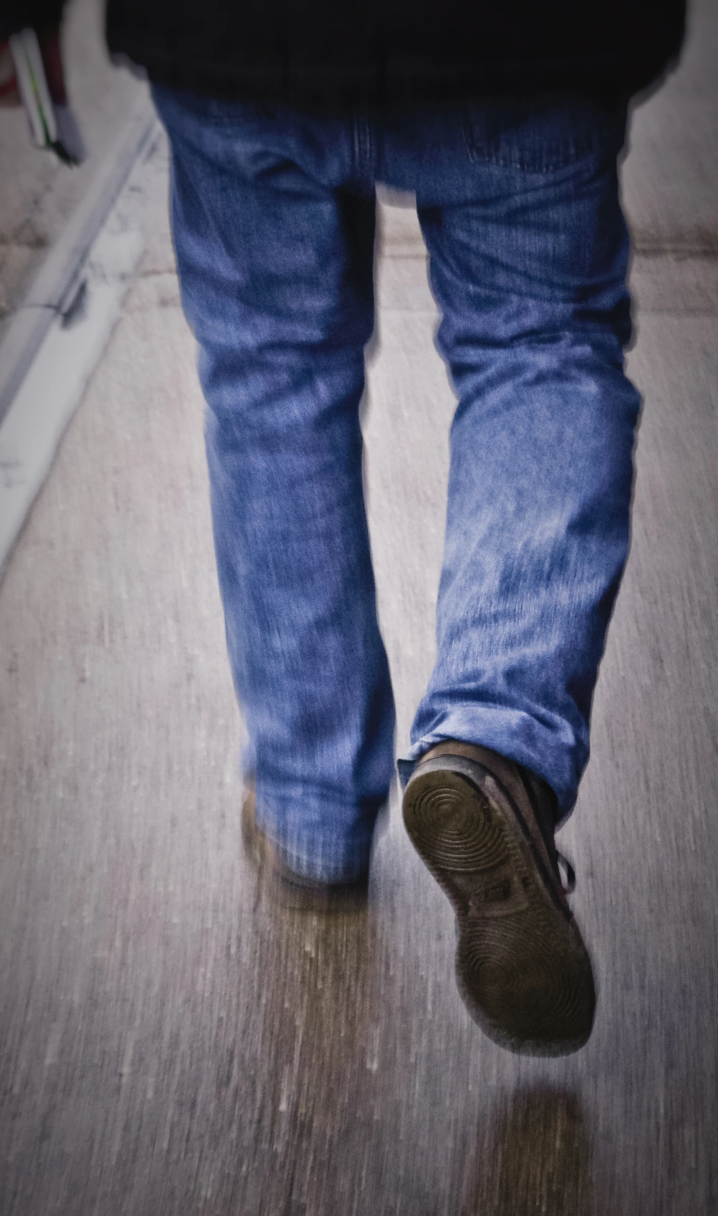 a person is walking down a walkway wearing dark shoes