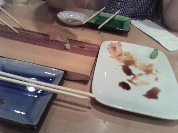 an assortment of food on a plate, with chop sticks, and a box on a table