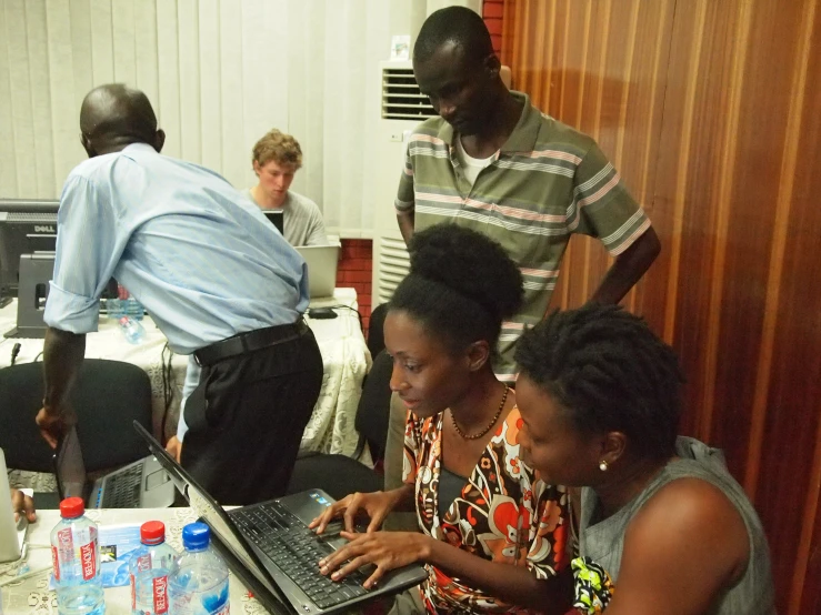 a group of people looking at the laptop together