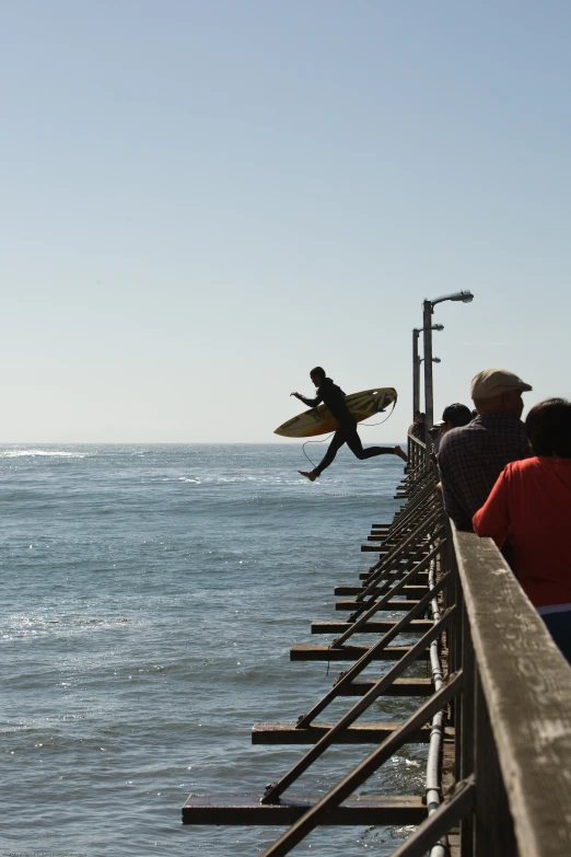 a man is jumping over a long barrier with his surfboard