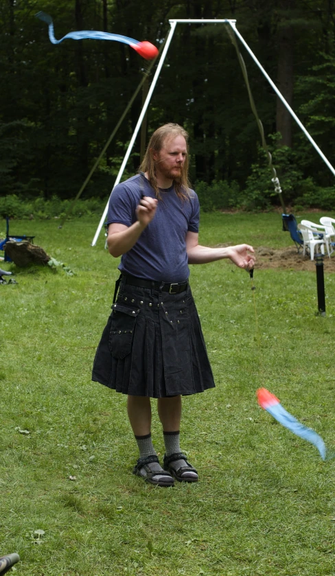 a man standing in a field with a kite flying overhead