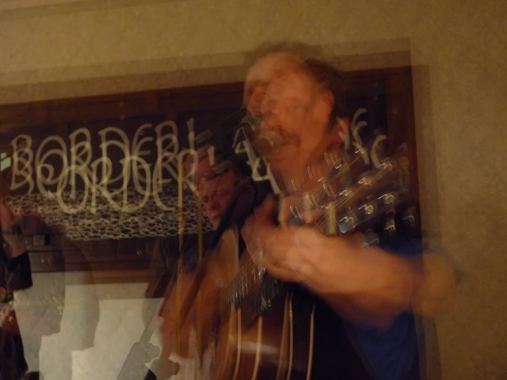 a man playing a guitar while another man with a band watches