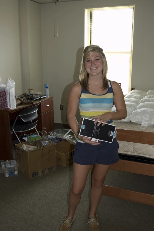 a girl holding up her laptop in a bedroom