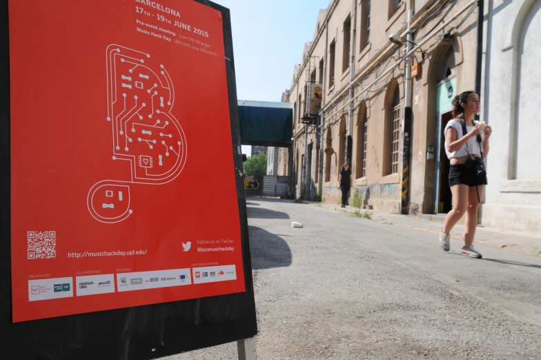 a woman walking past a red sign on the street