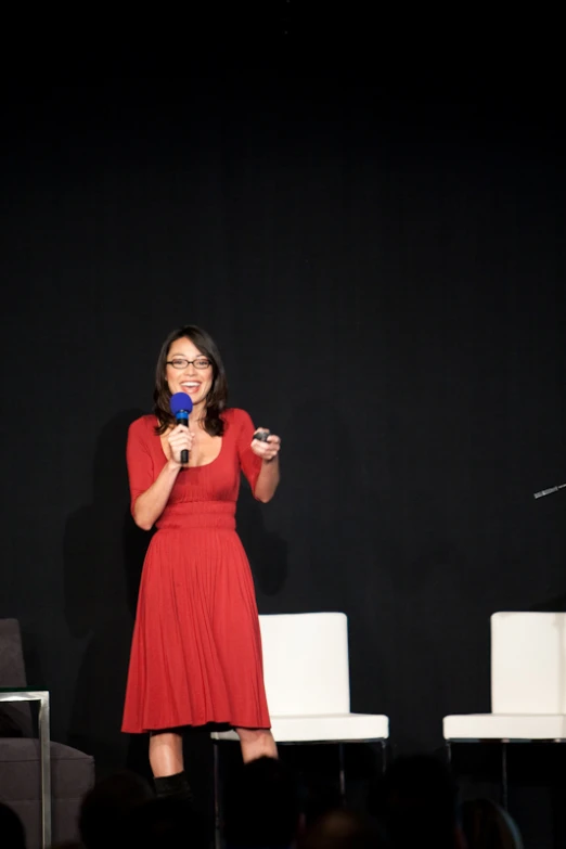 a woman on stage giving a speech with microphone in her hand