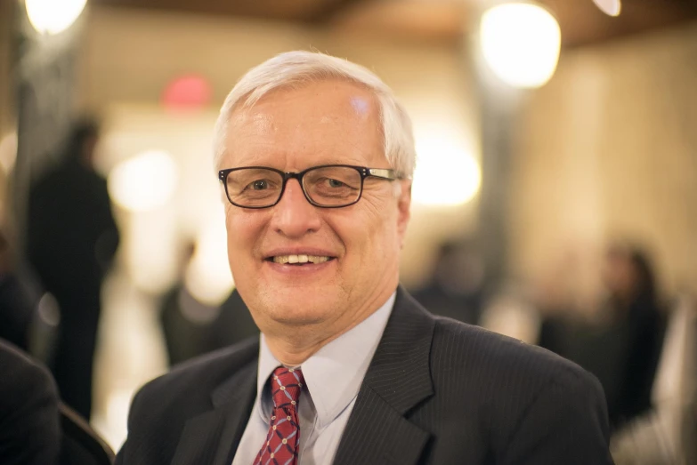 a man with glasses and a red tie is smiling