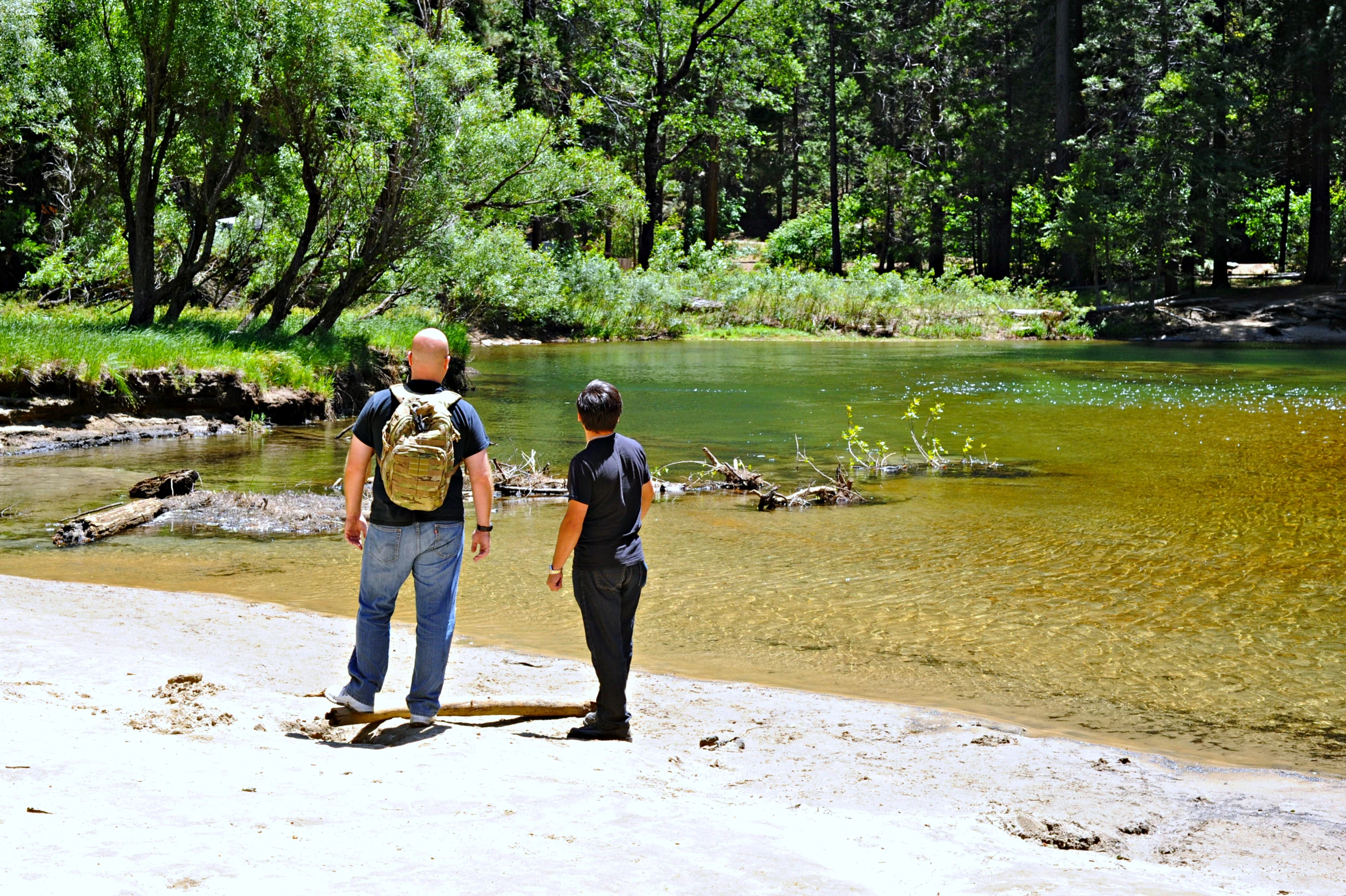 two people are standing by the side of a river