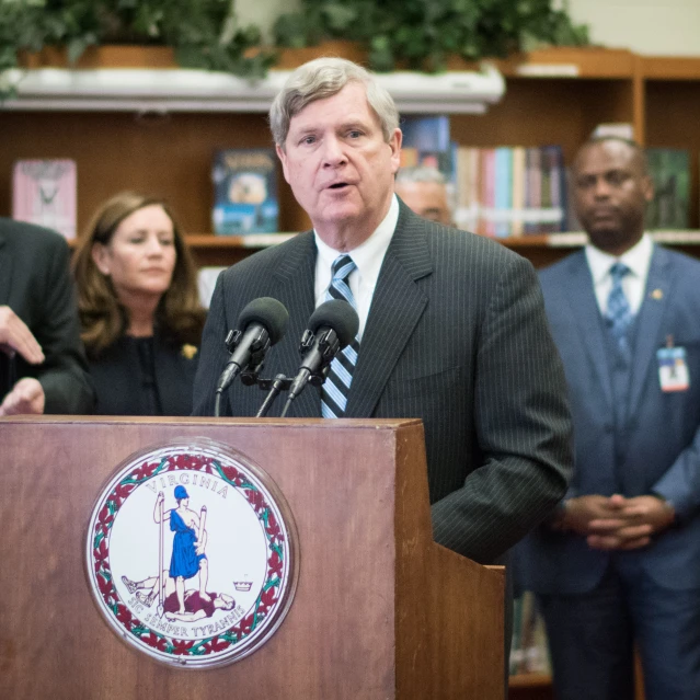 a man wearing a suit and tie speaking at a podium