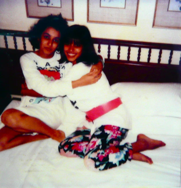 two s in pajamas hugging on a bed