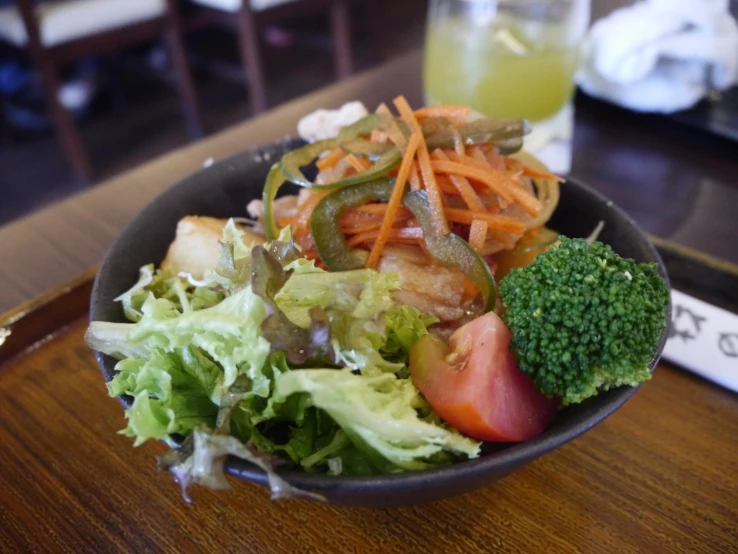 there is a black bowl with a salad on it