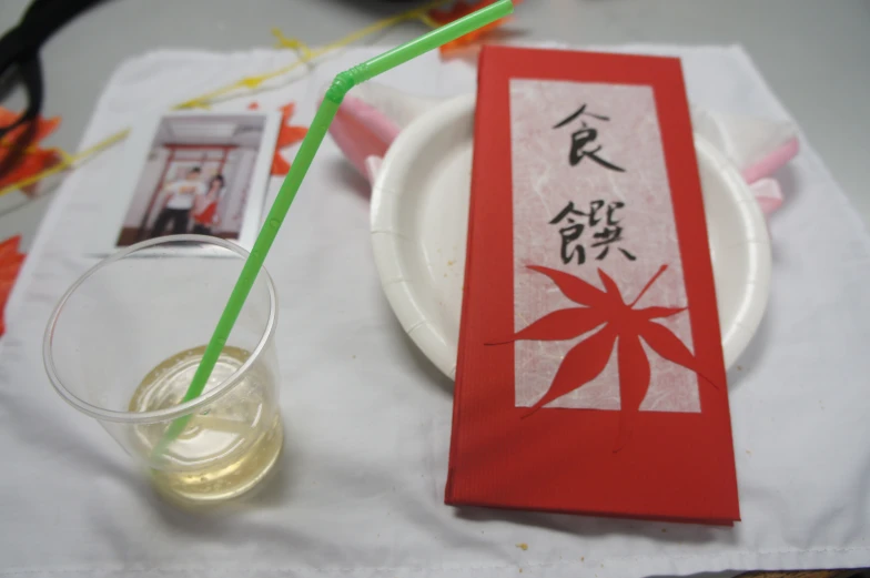 a paper drink and red book on a white tablecloth