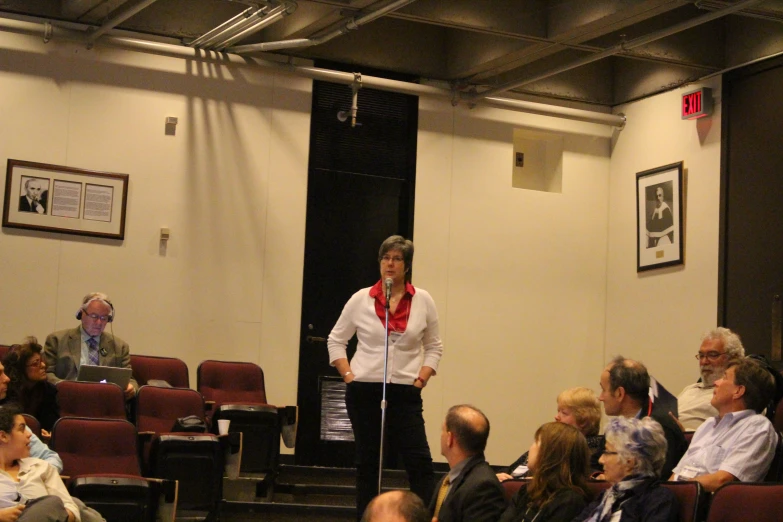 a woman stands on the stage in a room with a crowd