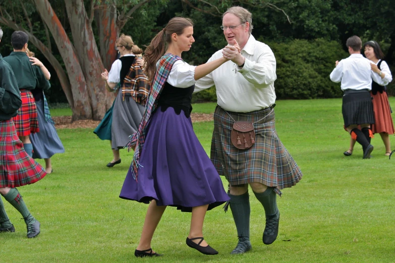 a man and woman dancing in kilts and medieval dress