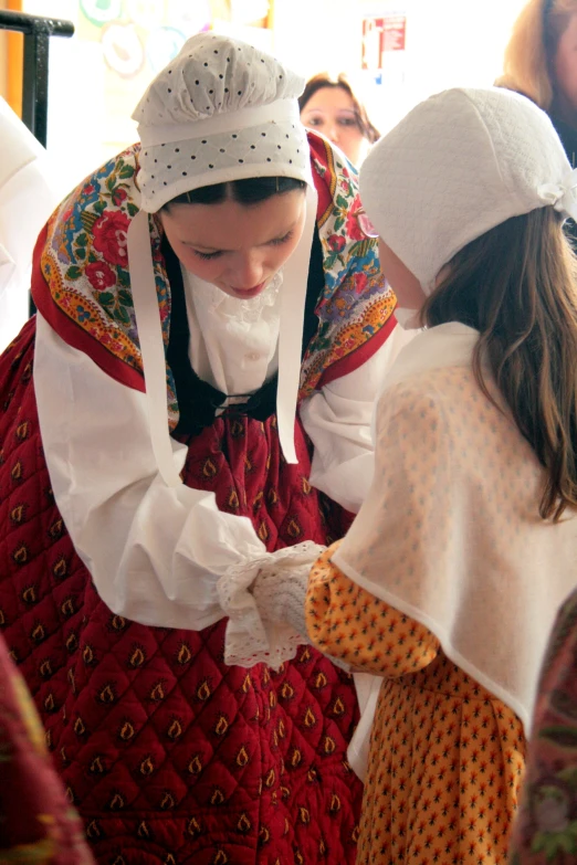 a woman in traditional polish clothing with small children