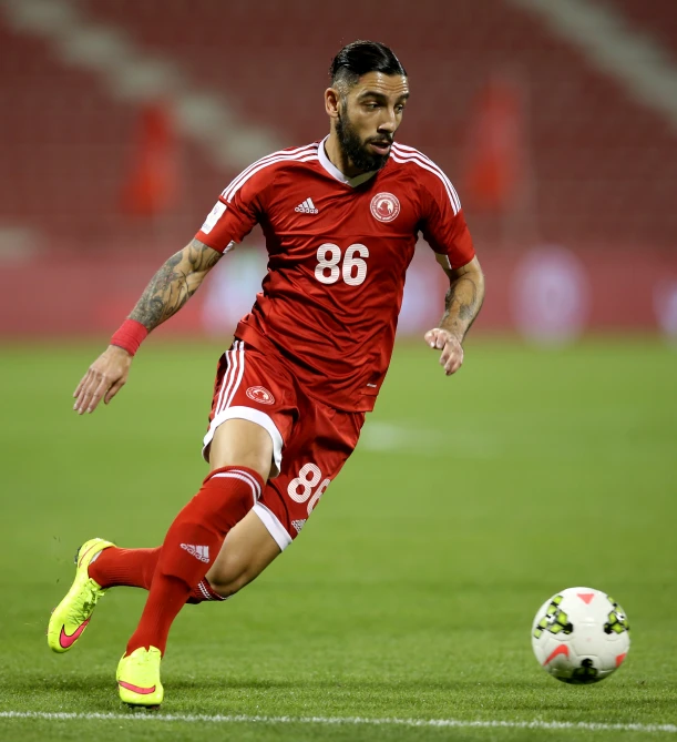 soccer player in red uniform on field near ball