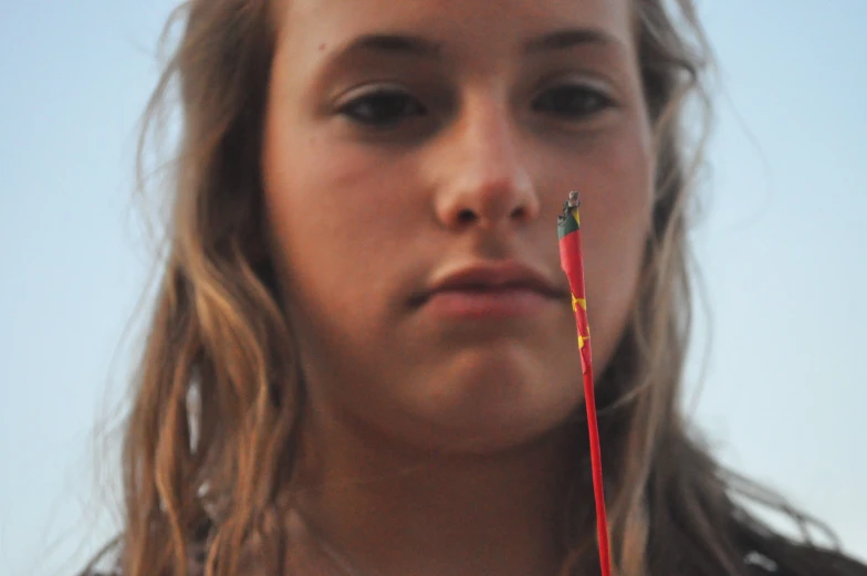 a woman holding a straw in her right hand and two wires stuck to the neck of her ear