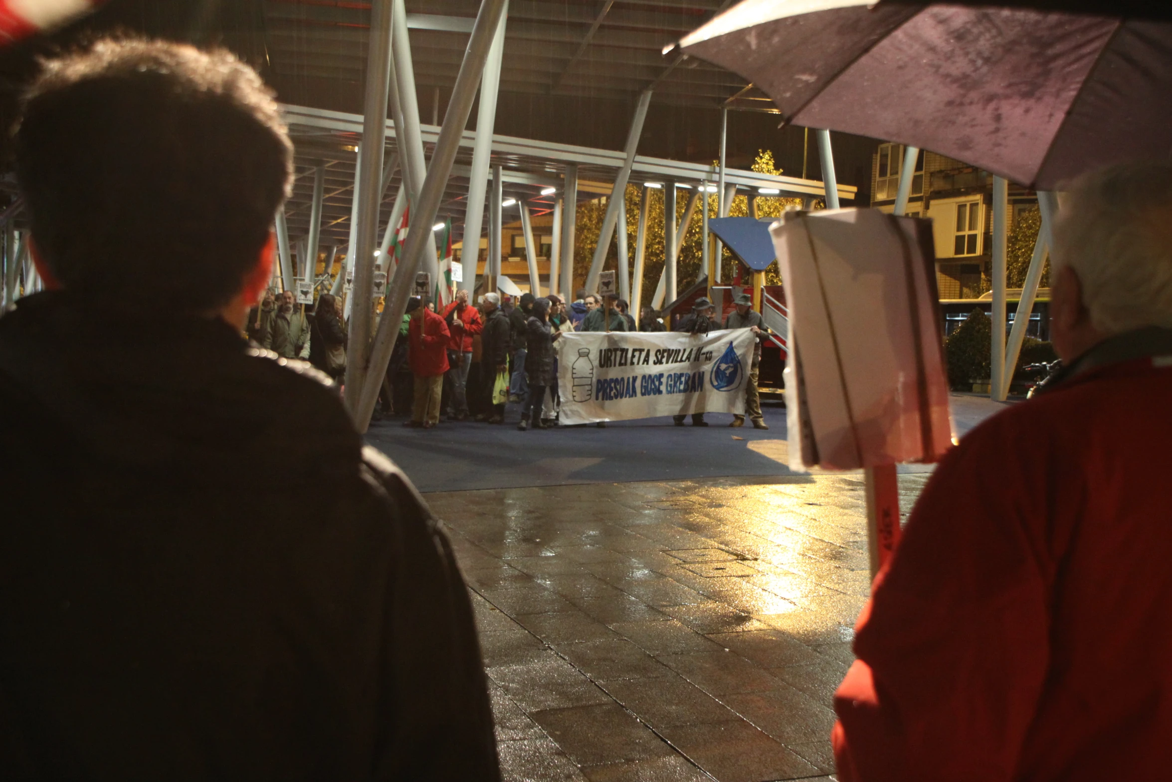 many people standing outside in line with umbrellas