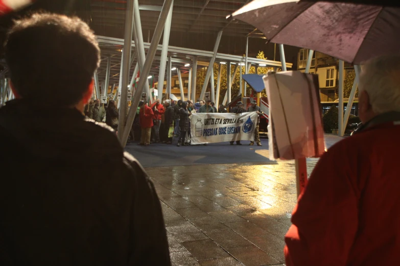 many people standing outside in line with umbrellas