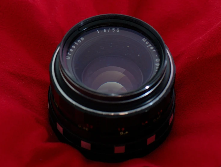 a camera lens sitting on top of a red cloth