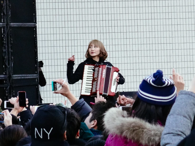 woman in dark dress playing accordion while onlookers take pictures