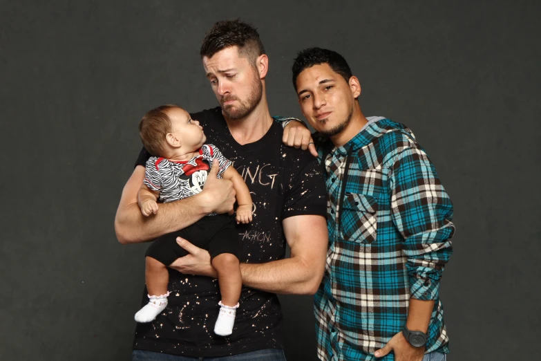 two men standing next to a baby in the middle