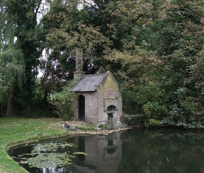 a stone building near the water with water lilies and trees around