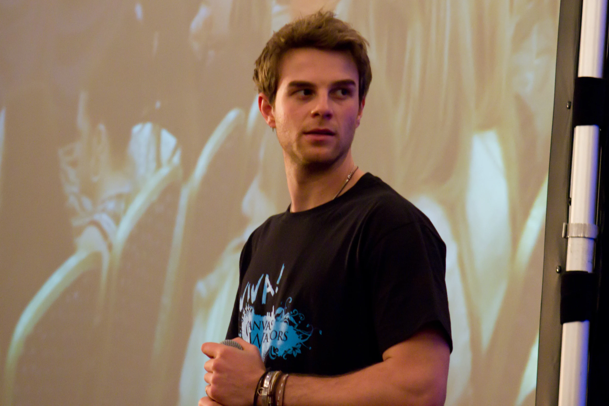 a man standing in front of a projection screen with his hands folded