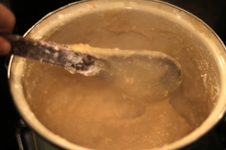 a ladle of  soup with a spoon sticking in