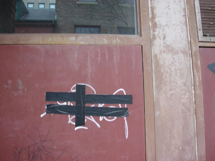 graffiti on the wall of an old building shows a cross