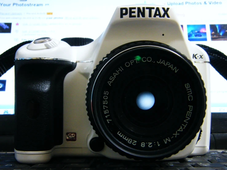 camera sitting on top of computer keyboard with pentax logo