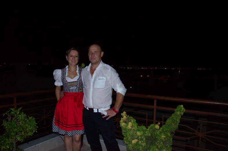 a man and woman wearing traditional bavarian clothing posing for the camera