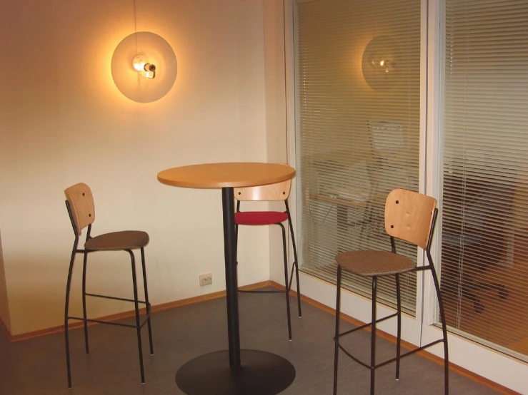 a small round table and chairs are in front of a window